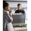 This image is a front-side view of the Rancilio Specialty RS1 espresso machine showcase picture with barista and customer with drink. 